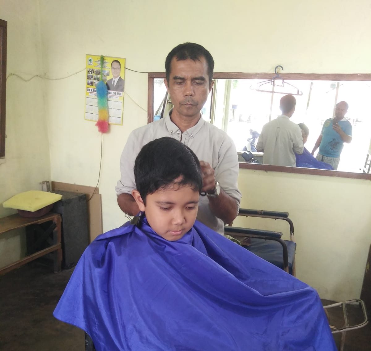 Agustawirya melakukan pekerjaannya sebagai tukang pangkas rambut.
